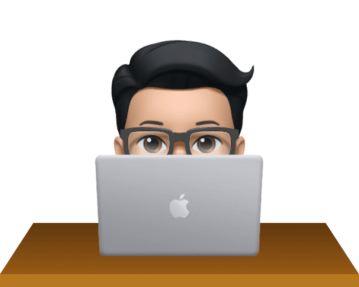 Dean Phommahaxay Memoji avatar sitting at brown desktop with silver Macbook laptop.